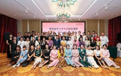 Second group photograph of training course participants seated and standing under a chandelier